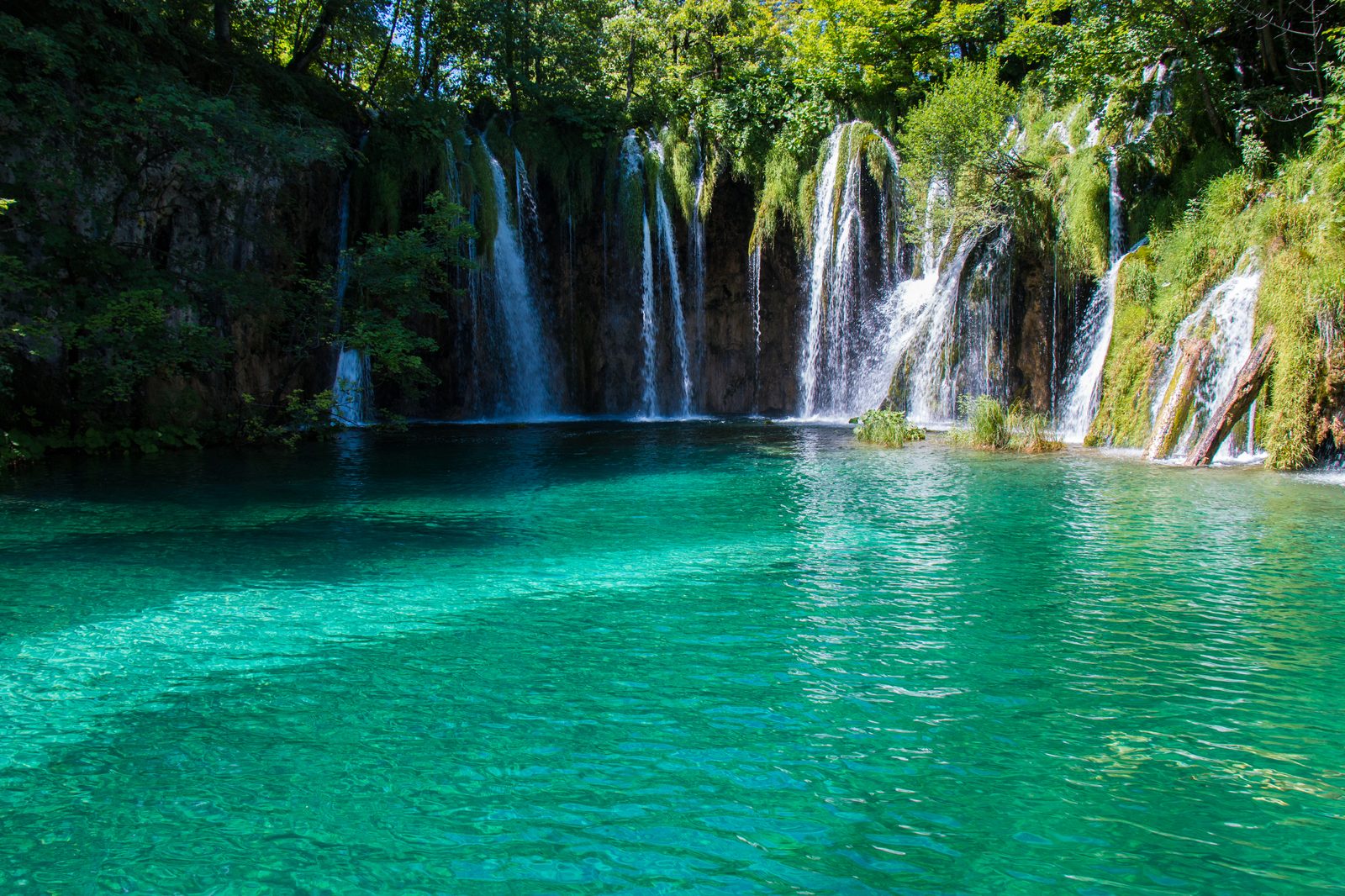 Boardwalks crossing one of the cascading lake basins at Plitvice — turquoise water and falling water on every side