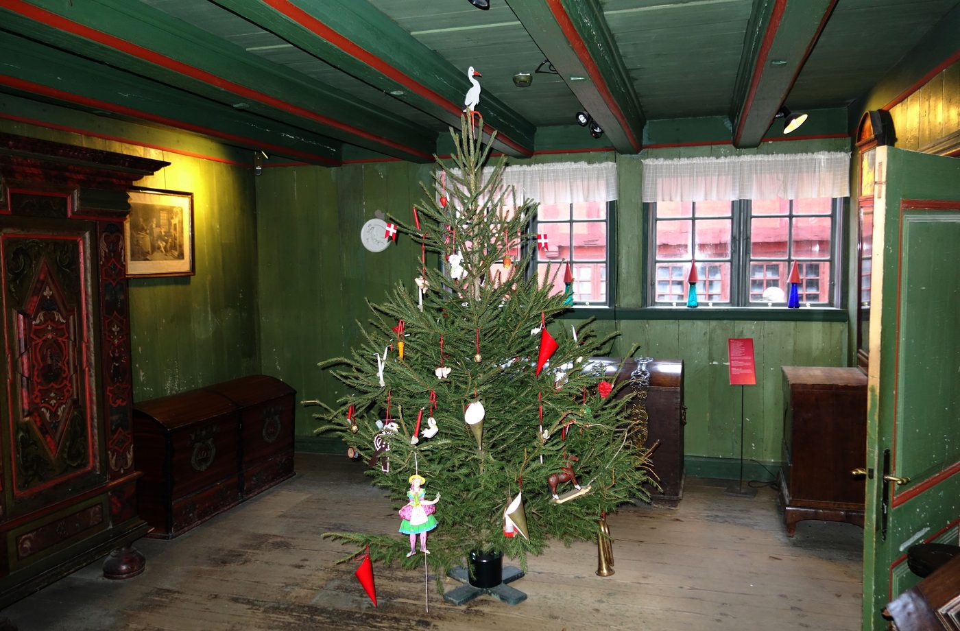 A historic merchant house and Christmas tree at the Den Gamle By open-air museum in Aarhus, lit at dusk