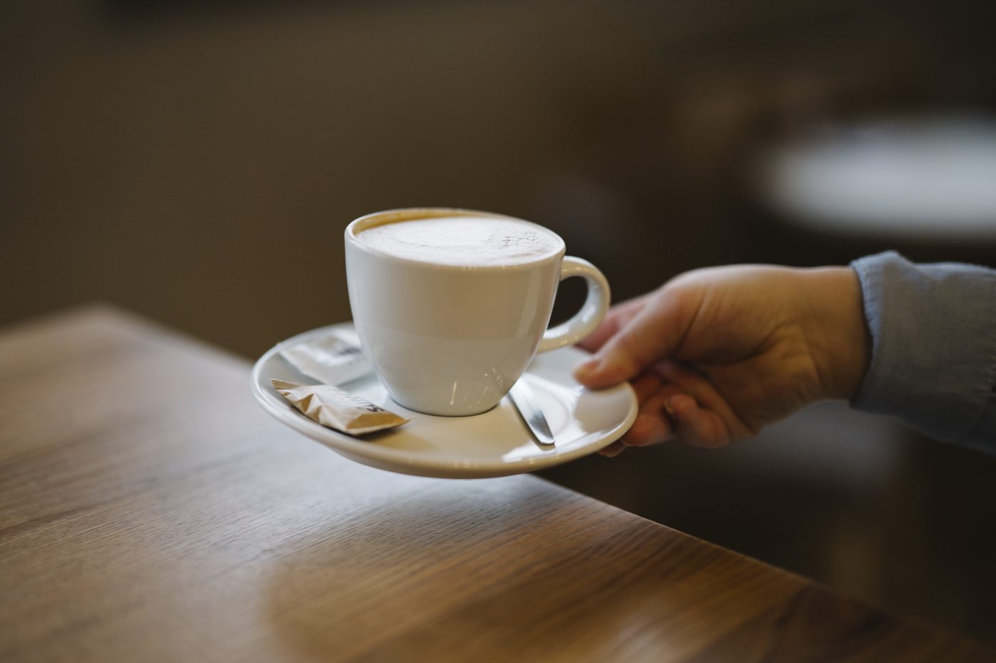 A warm cup of coffee on a wooden café table — the still life of a Danish afternoon