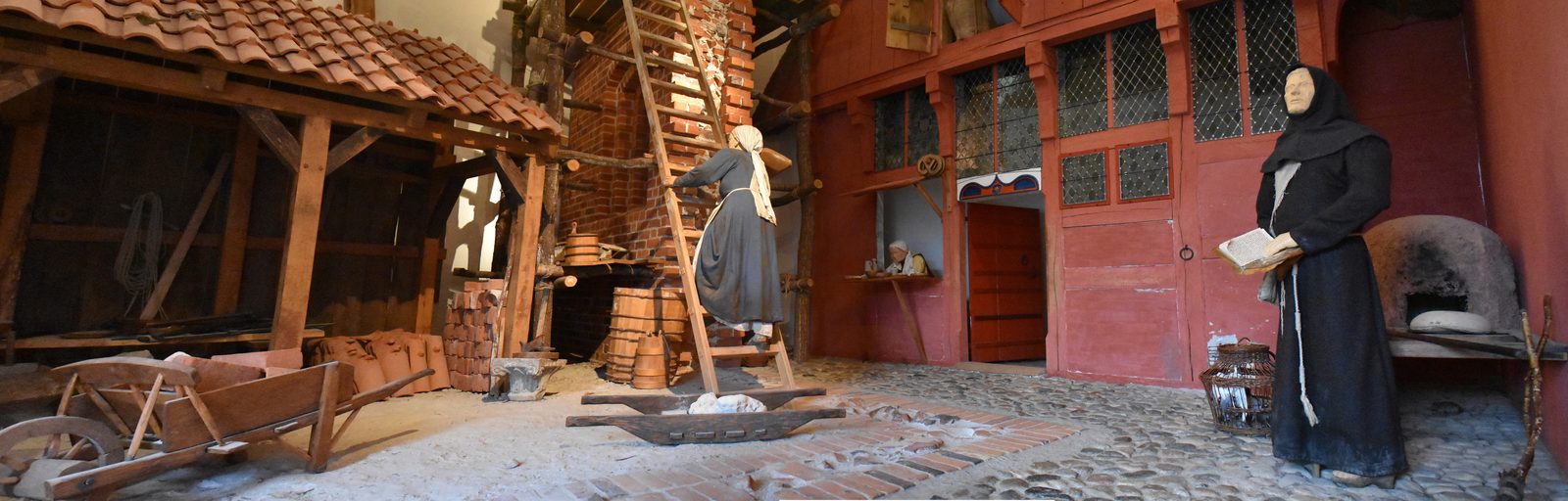 Inside Museet Ribes Vikinger — recreated Viking-age longhouse interior with beds, hearth and craft tools