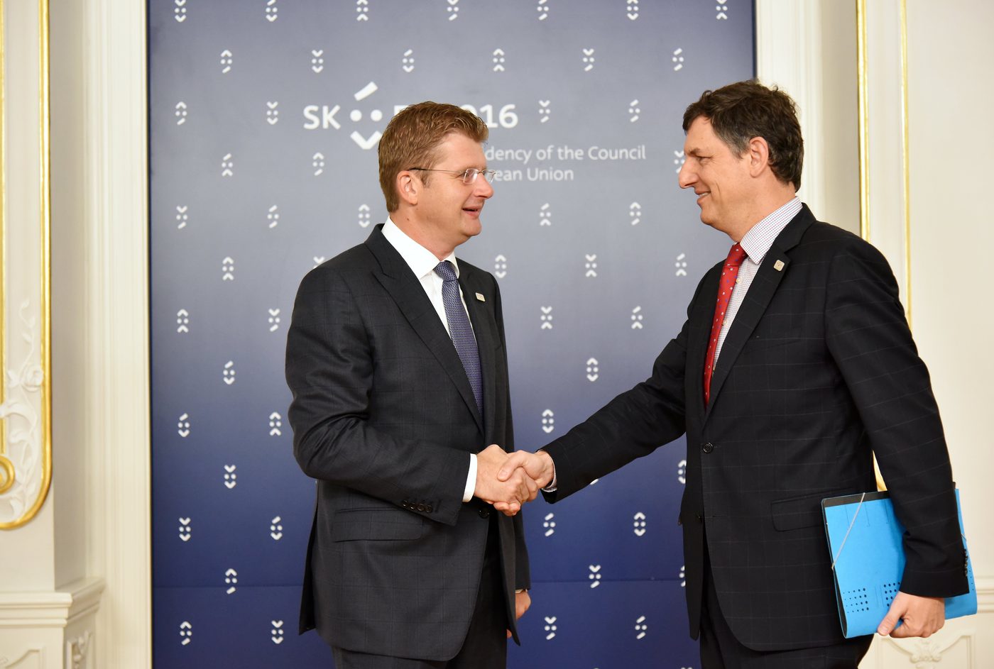 A formal handshake between two people in business attire — the standard Danish greeting, even on a first meeting in private