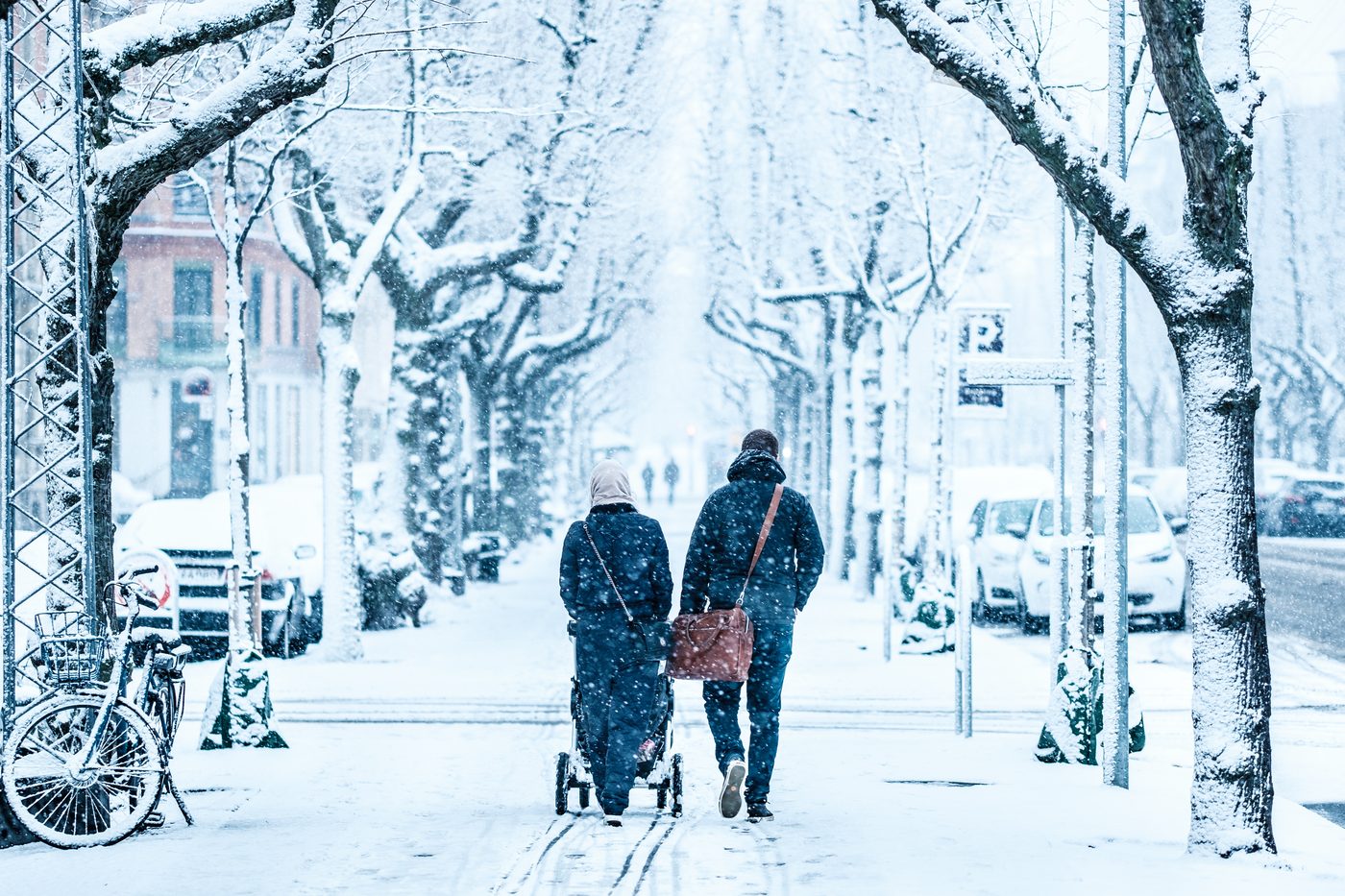 A family walking through deep snow on Frederiksberg Allé in Copenhagen on a bright winter day